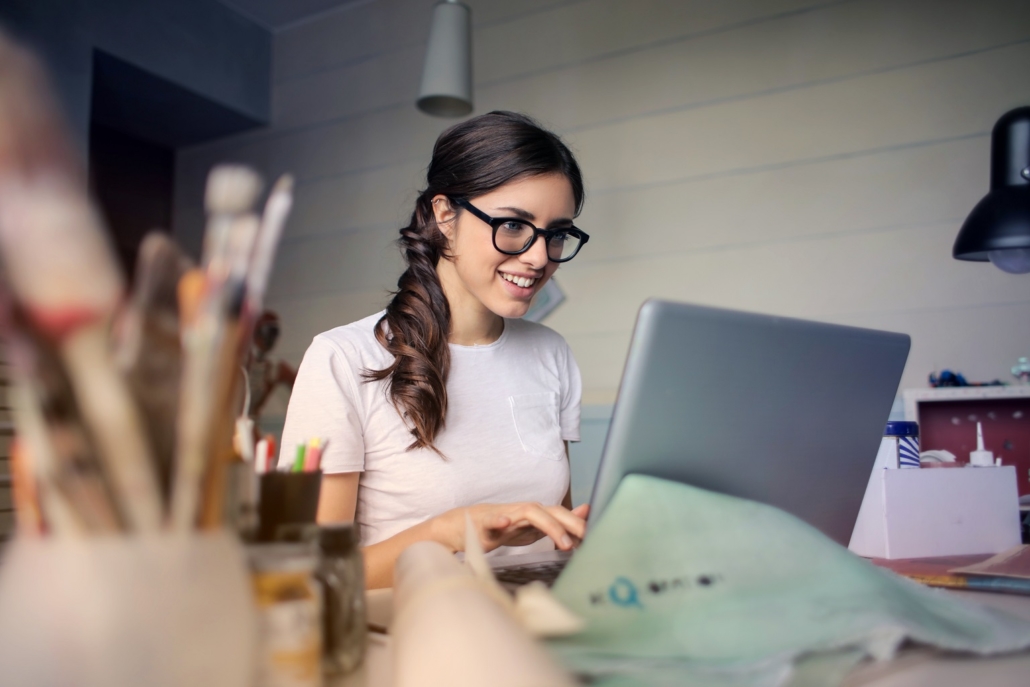 Happy young woman white a white smile working at a computer