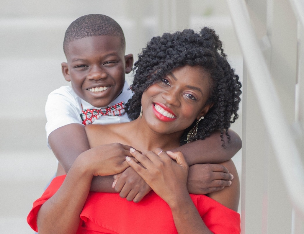 Mom in a red dress with her son smiling and posing for a photo