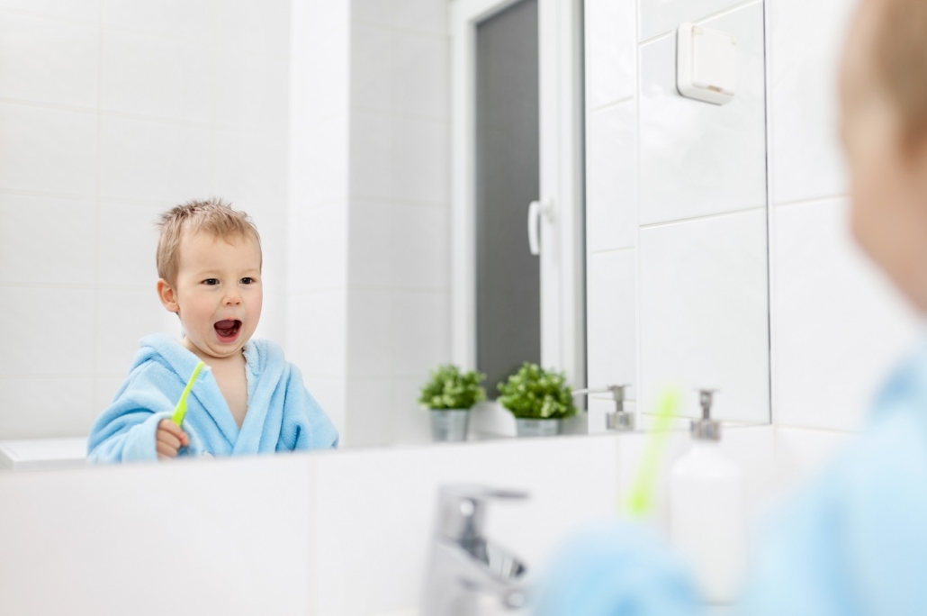 photo of young boy brushing teeth in the bathroom developing good early dental habits